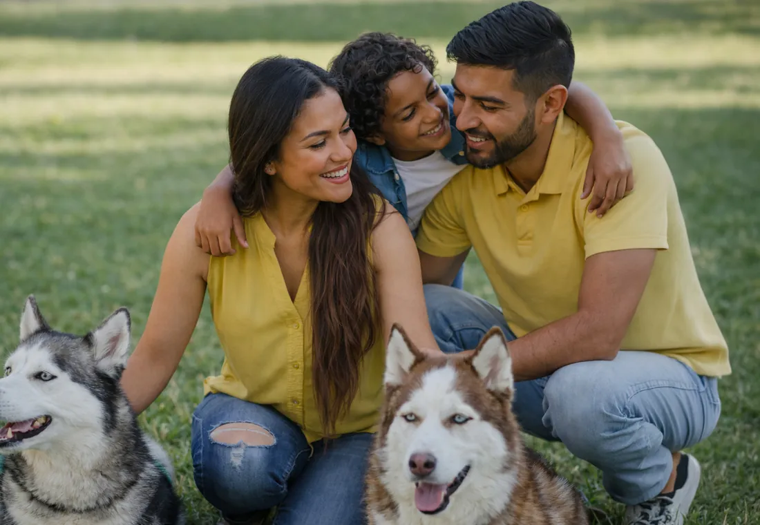 Familia joven jugando en el parque con sus dos perros