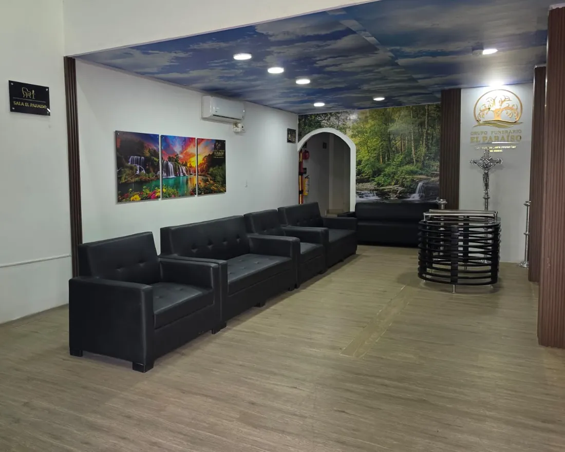 Sala de velación El Paraíso: sofás, aire acondicionado y un mural de naturaleza al fondo